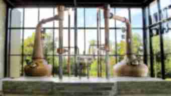 Two very large copper stills sit in front of a wall of windows at the Lexington Brewing and Distilling Co.