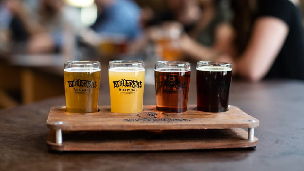 A flight of four beers from Ethereal Brewing in a wooden holder.