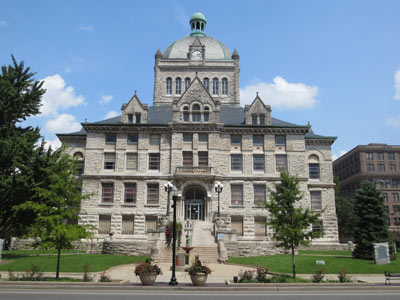 Large, old, regal building with domed top made of grey textured stone. 