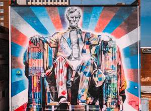 A large mural of Abe Lincoln sitting painted in brightly colored patterns primarily with red, blue, and white.