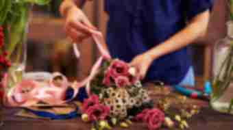 Someone ties a bow around flower arrangement